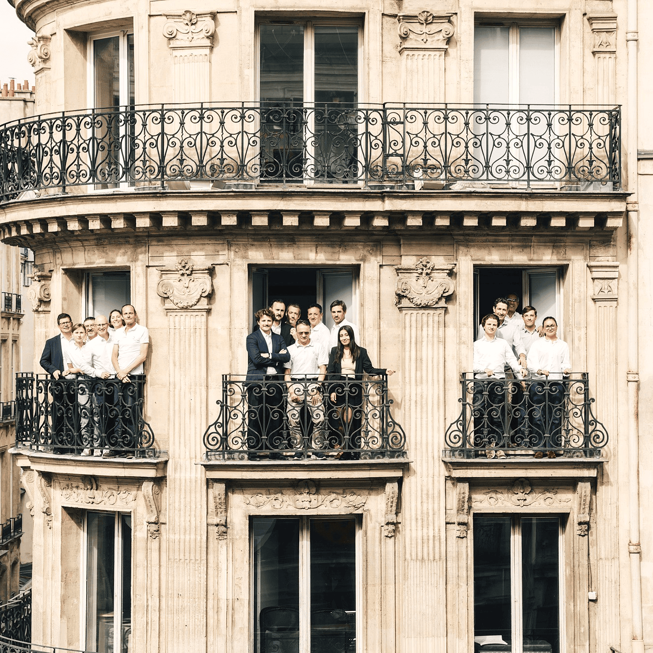 Photo d'un immeuble Hausmanien avec les équipes de Quintess aux balcons souriants.
