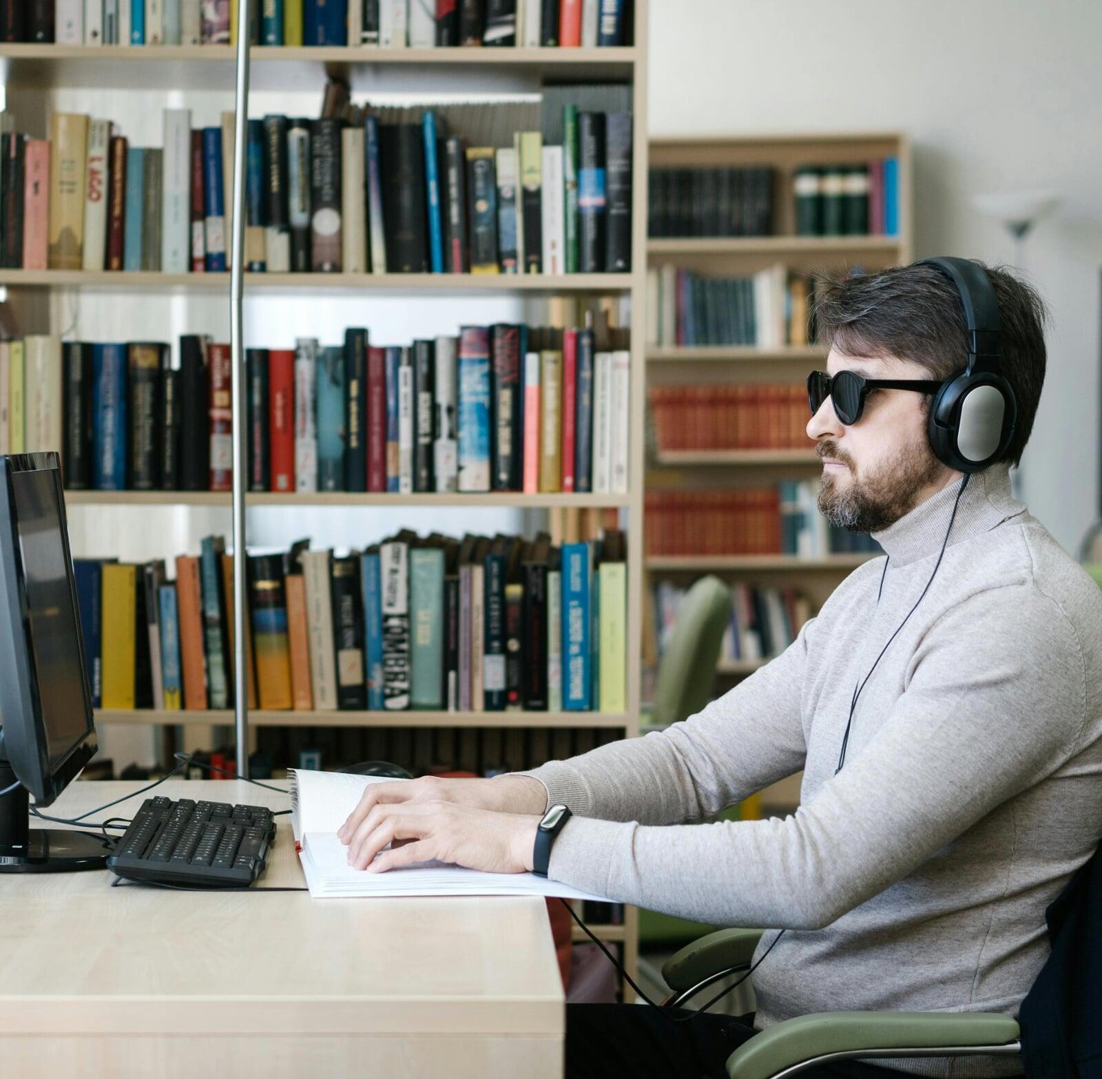 Un homme malvoyant assis à son bureau se connecte à son espace bancaire